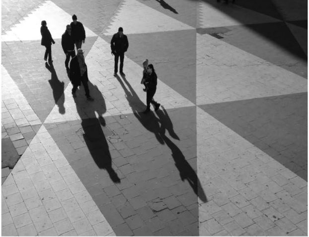 Personer med långa skuggor som går på Sergels torg